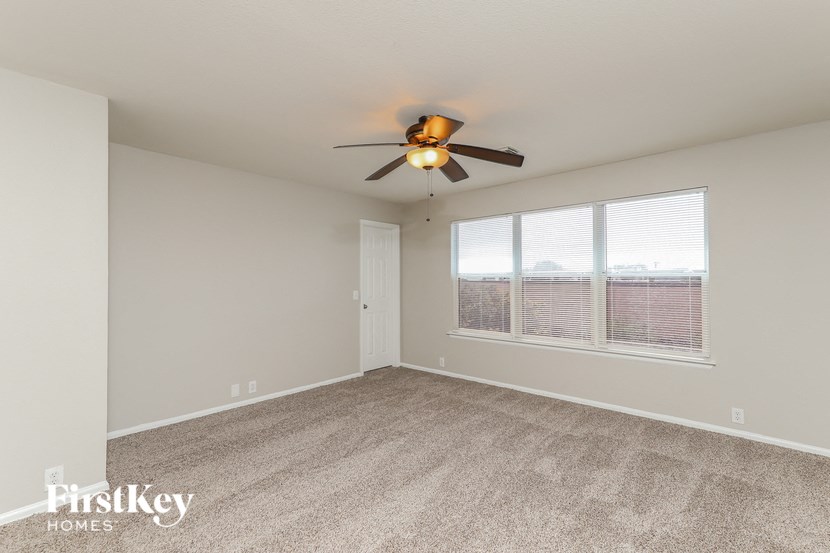 a spacious living room with a ceiling fan and a large window