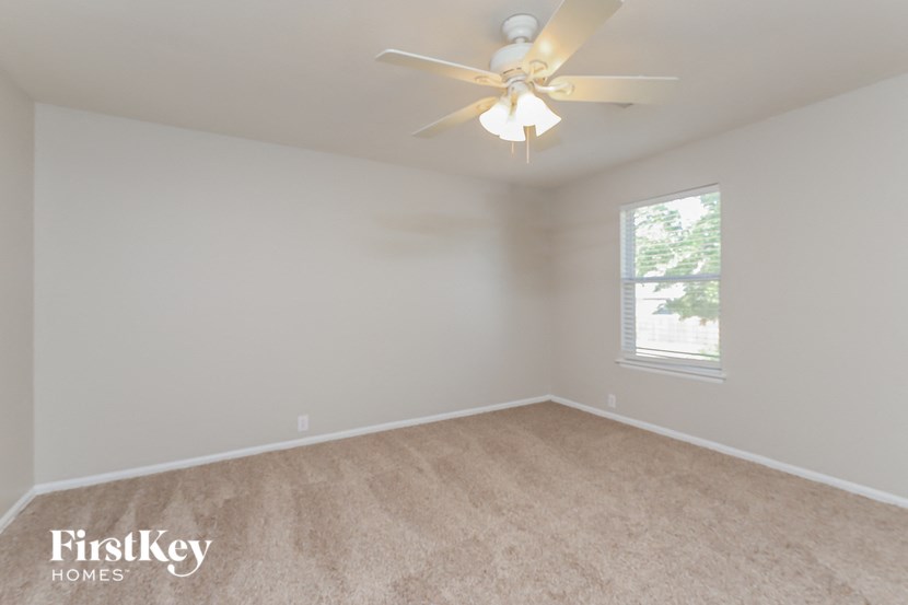 an empty bedroom with a ceiling fan and a window