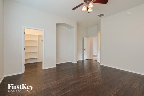 an empty living room with a ceiling fan and a closet