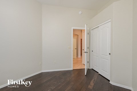 a bedroom with white walls and wood flooring and a door to a hallway
