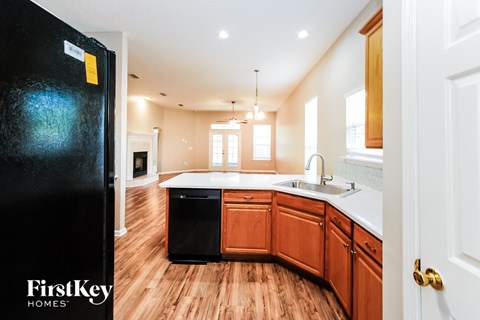 A kitchen with wooden cabinets and a black fridge is shown.