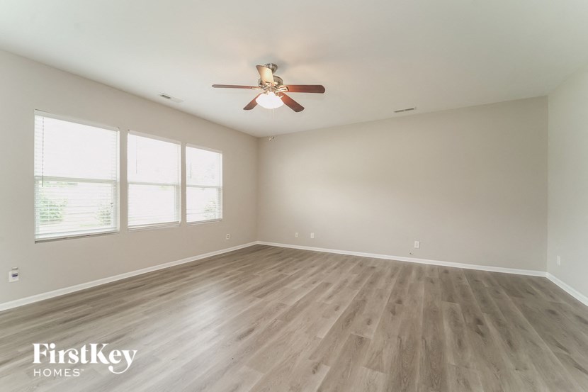an empty living room with a ceiling fan and wood floors