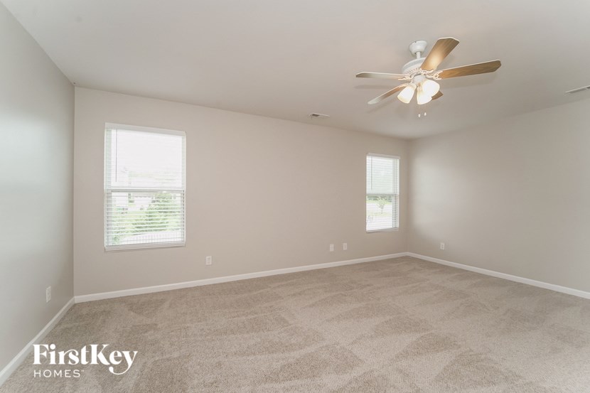 an empty room with a ceiling fan and two windows