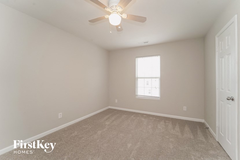 an empty bedroom with a ceiling fan and a window