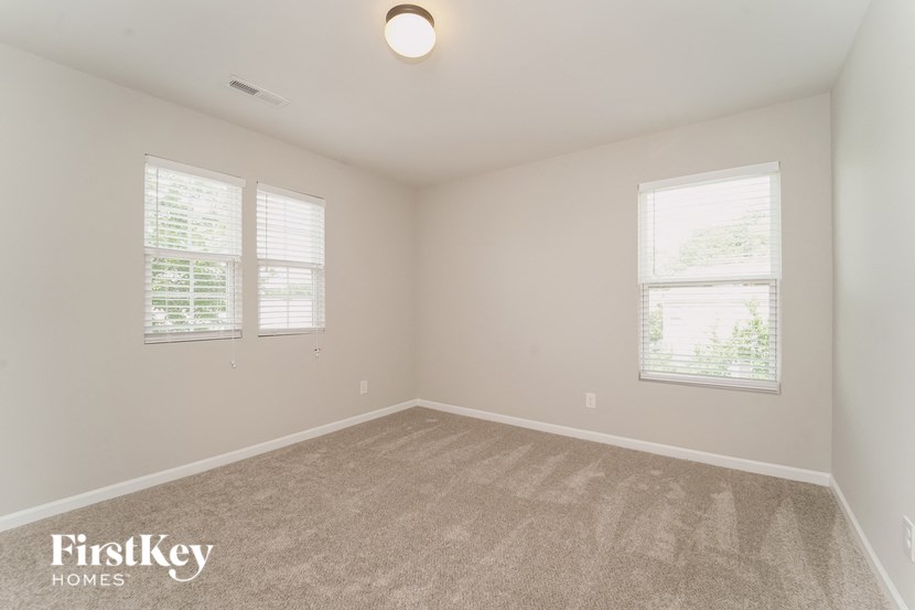 a bedroom with two windows and a carpeted floor