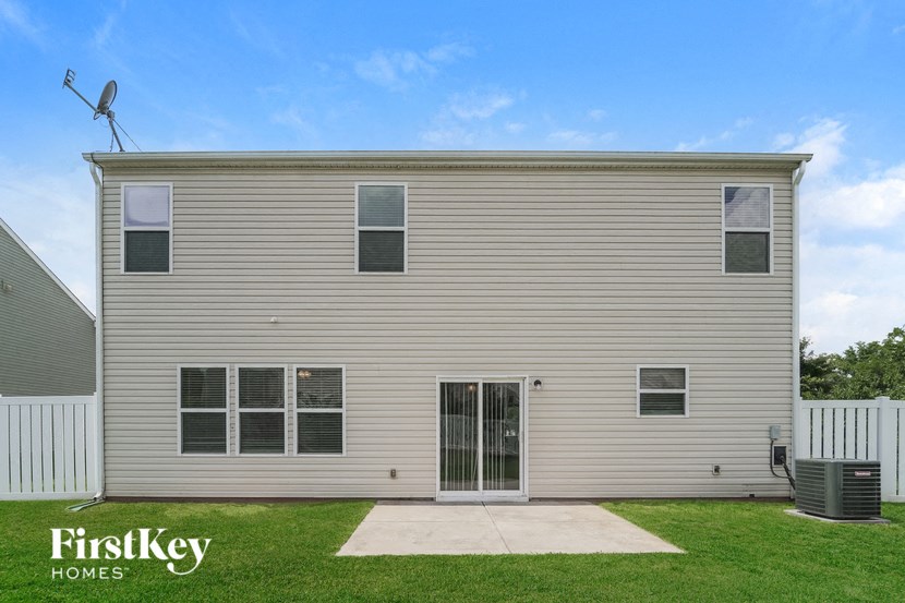 the front of a house with a grass yard and a wind turbine