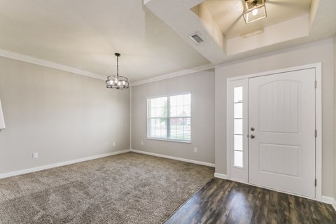 an empty living room with a white door and a window