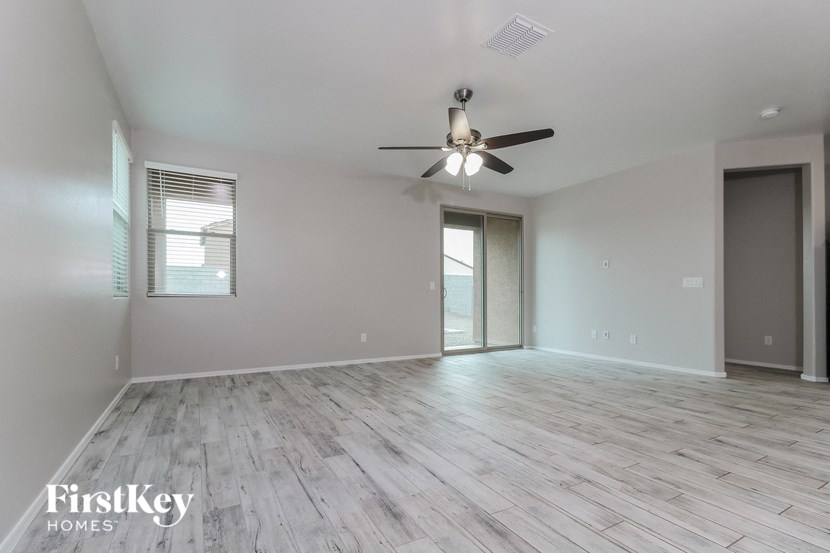 an empty living room with a ceiling fan and a window