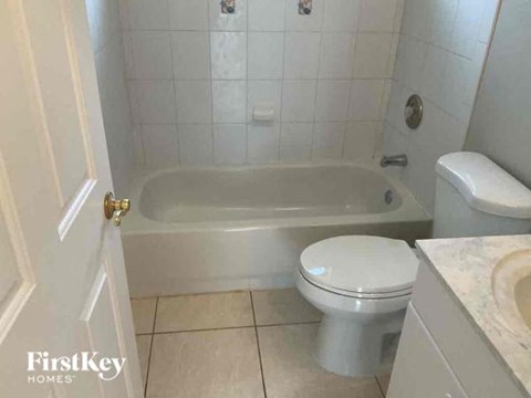 a white bathroom with a toilet and a bath tub