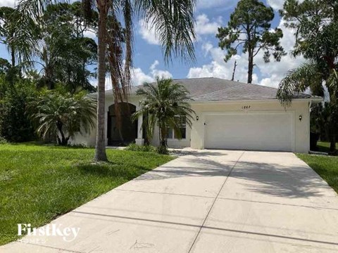 a white house with a garage and palm trees