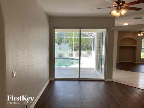 an empty living room with a sliding glass door to a pool