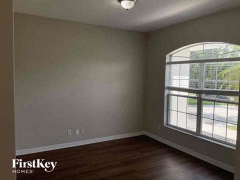 an empty bedroom with a large window and wooden floors