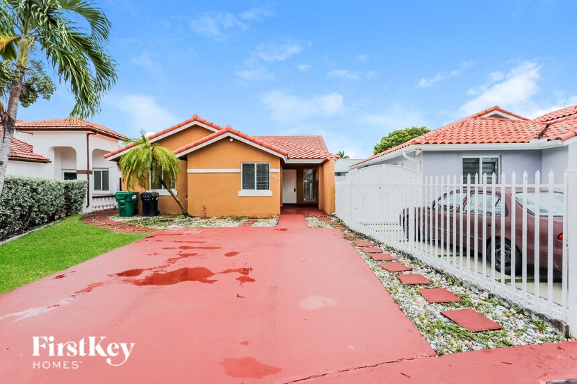 A red brick house with a white fence in front of it.