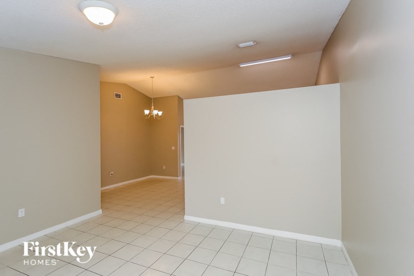 A room with a white tile floor and a chandelier hanging from the ceiling.