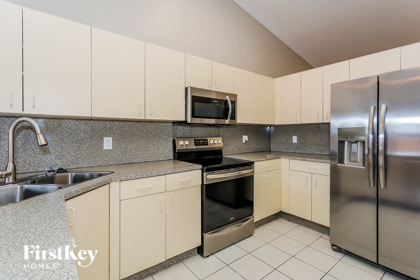 A kitchen with a stainless steel refrigerator, microwave, and oven.