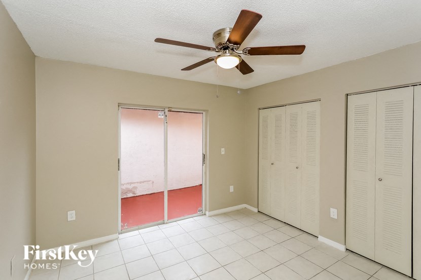 A room with a ceiling fan and a sliding glass door.