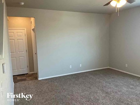 A room with a carpeted floor and a ceiling fan.