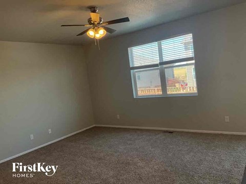 A room with a ceiling fan and a window with blinds.