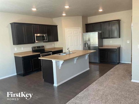 A kitchen with black cabinets and a white door.