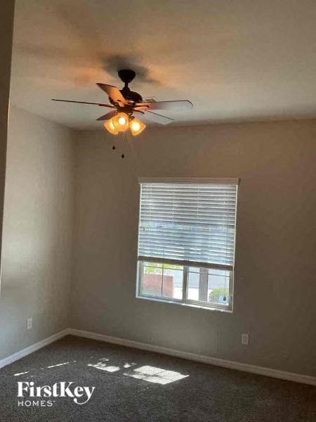A room with a ceiling fan and a window with blinds.
