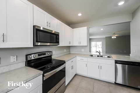 a kitchen with white cabinets and a stove and a microwave