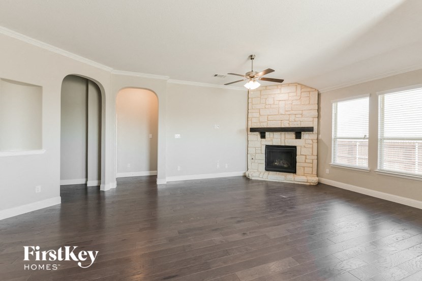 an empty living room with a fireplace and a ceiling fan