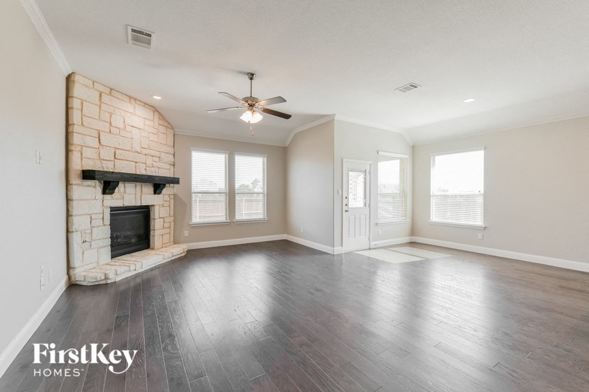 an empty living room with a fireplace and a ceiling fan