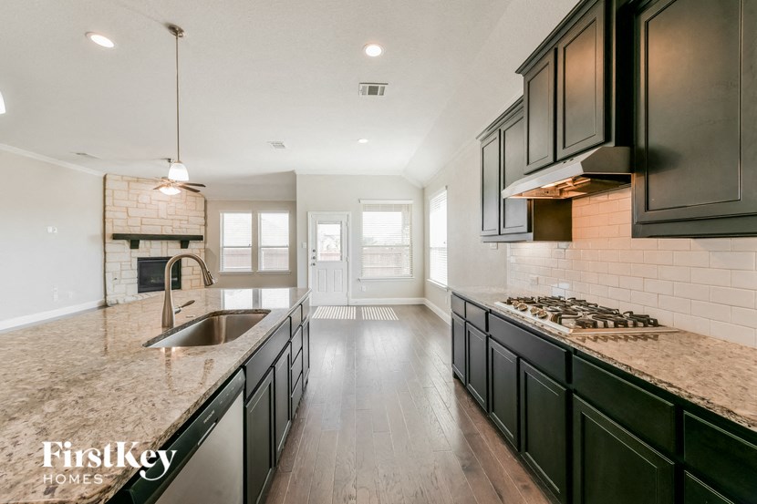 a kitchen with black cabinets and granite counter tops and a sink