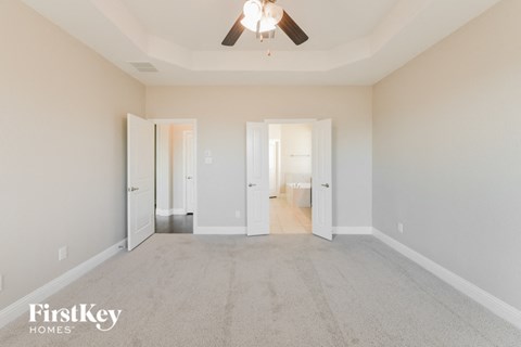 a spacious living room with carpet and a ceiling fan