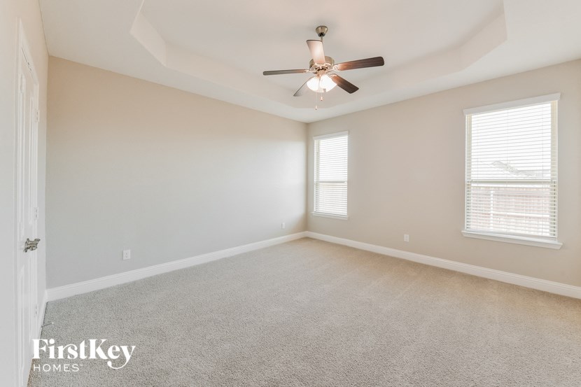 the spacious living room with ceiling fan and carpeting