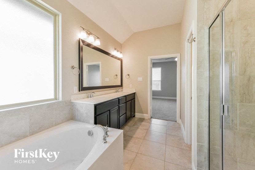 the master bathroom has a large tub and a walk in shower