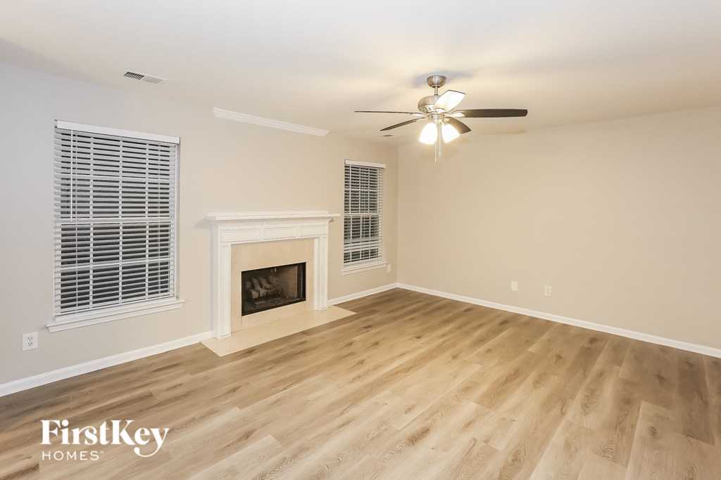 A spacious room with a fireplace and a ceiling fan.
