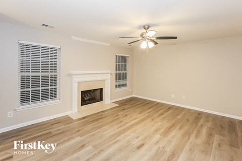 A spacious room with a fireplace and a ceiling fan.