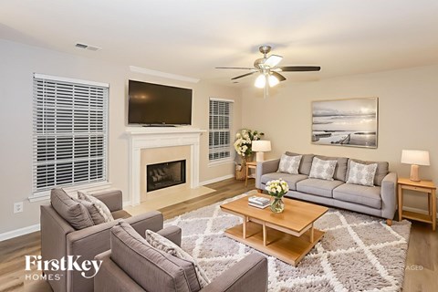 A living room with a grey couch, a coffee table, a fireplace, and a television.