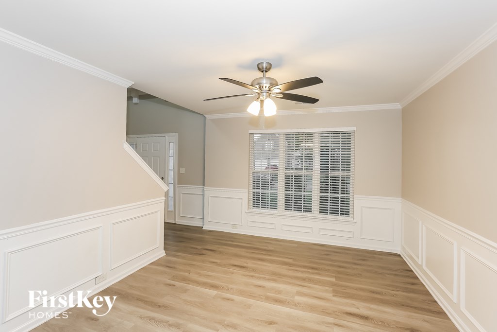A room with a ceiling fan and wooden flooring.