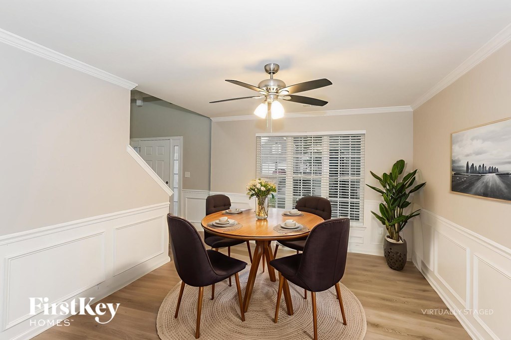A dining room with a table set for four and a ceiling fan.