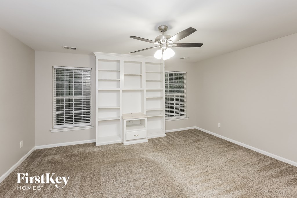 A room with a ceiling fan and a built-in shelf unit.