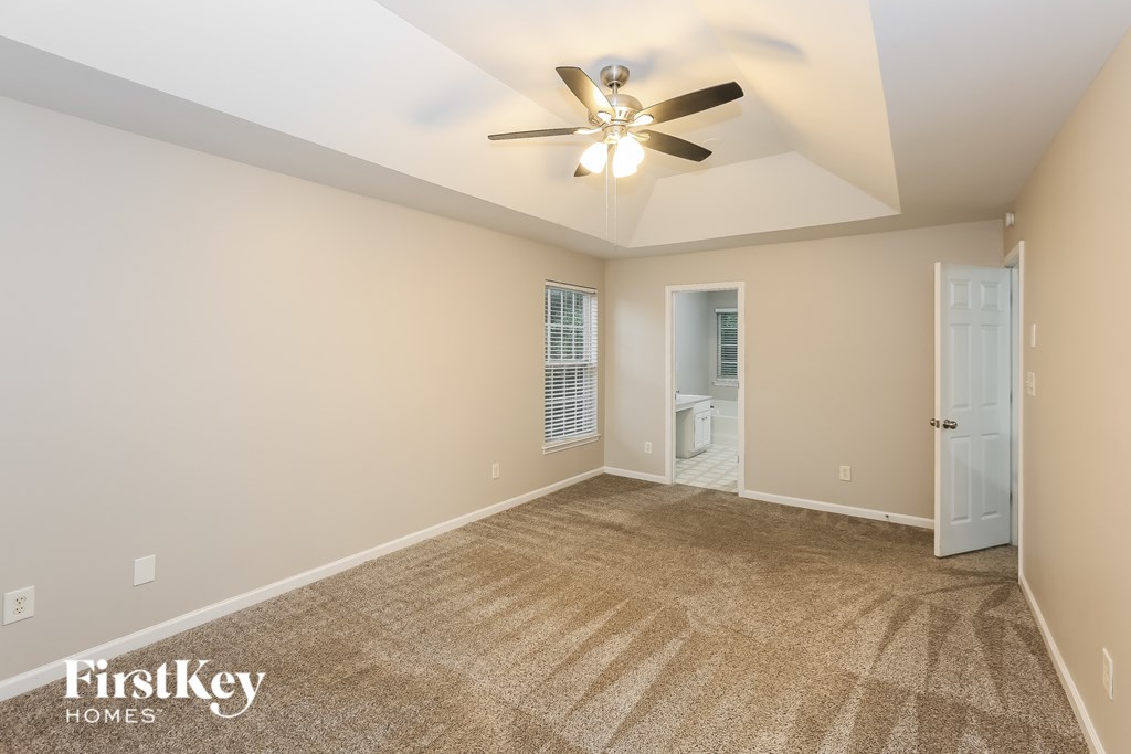 A room with a carpet floor and a ceiling fan.