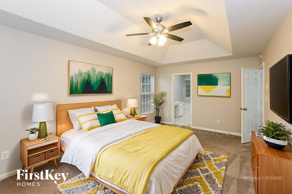 A bedroom with a bed, a ceiling fan, and a painting on the wall.
