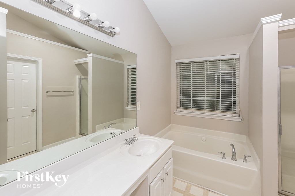 A white bathroom with a tub, sink, and mirror.