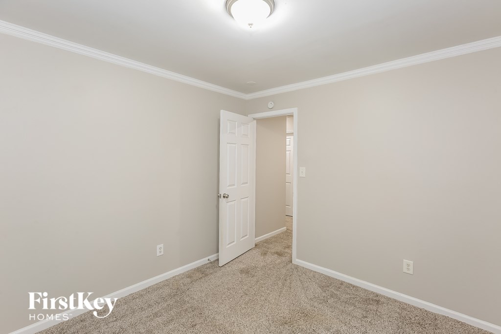 A carpeted hallway with a door on the left and a light on the ceiling.