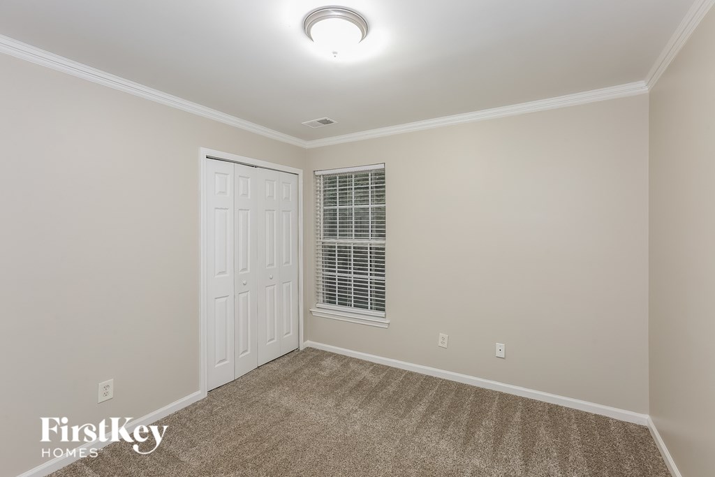 A room with a white door and a window with blinds.