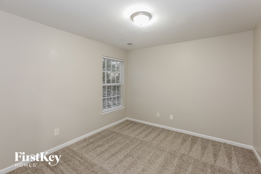 A carpeted room with a window and a light on the ceiling.