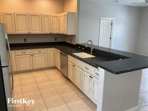 A kitchen with white cabinets and black countertops.