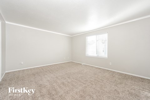 a spacious living room with carpet and a window