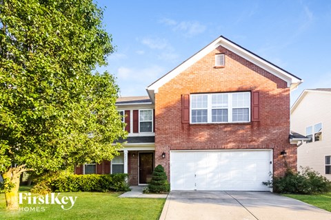 a white garage door in front of a brick house with a tree