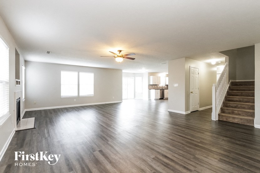 an empty living room with wood floors and a ceiling fan