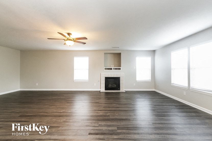 an empty living room with a fireplace and a ceiling fan