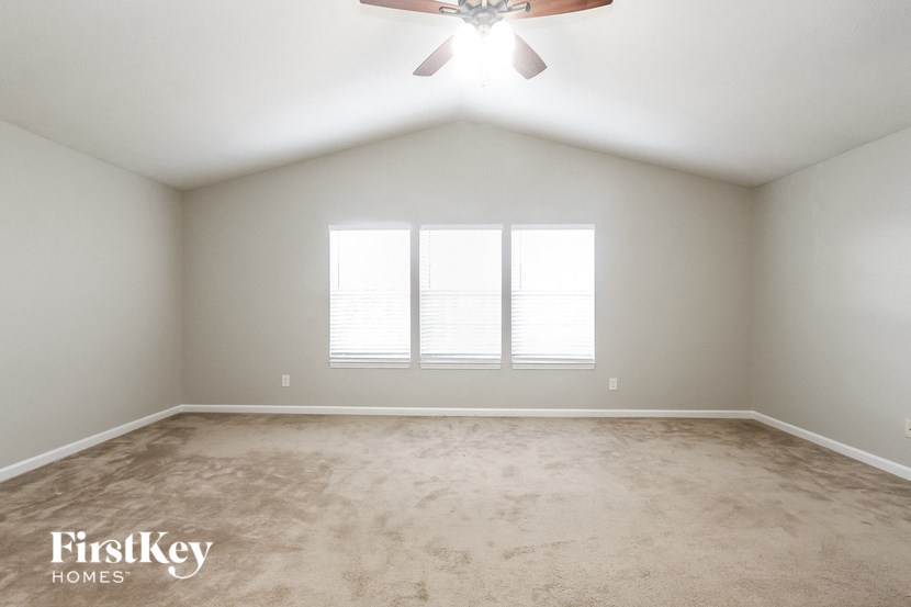 a empty bedroom with a ceiling fan and two windows