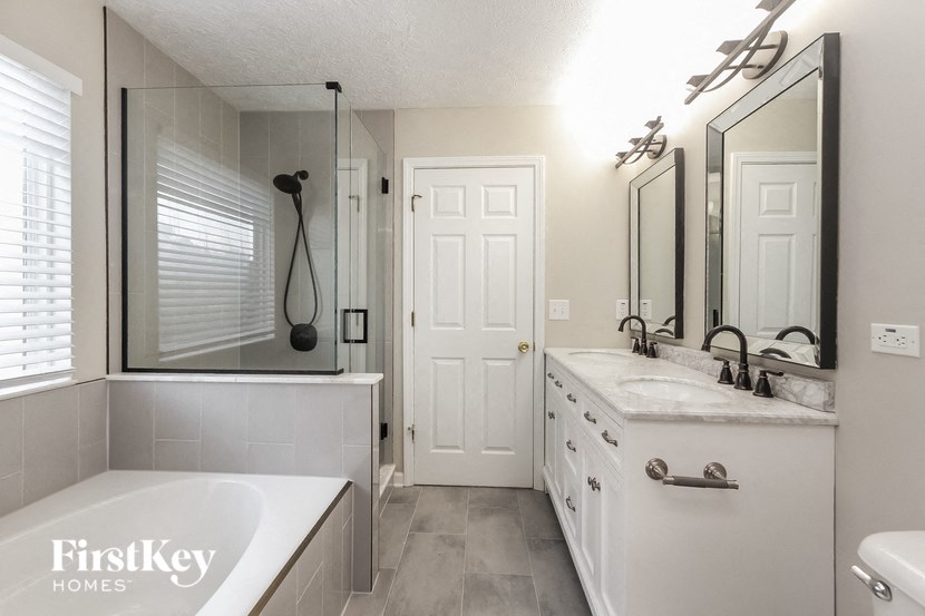 a white bathroom with a tub and a sink and a mirror